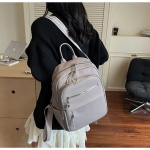 Detail of greyish-purple litchi grain leather backpack with multi-zipper compartments