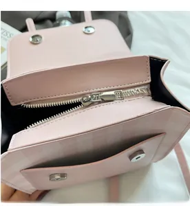 Detail view of pink plaid handbag showing smooth silver zipper and magnetic buckle closure