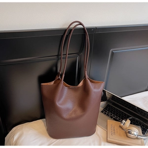 Close-up of deep brown lychee grain leather tote bag with elegant laptop and accessories