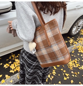 Détail du sac seau à carreaux vintage avec pendentif cœur sur fond de feuilles d'automne