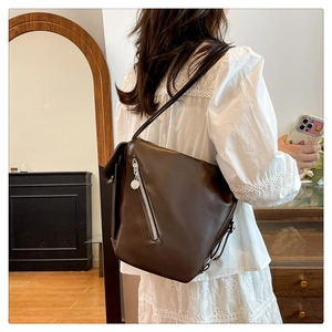 Detail of minimalist dark brown leather tote with diagonal silver zipper and metallic puller