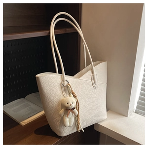 Detailansicht der weißen Totebag mit Litschi-Muster, Bärenanhänger und Seidenschal