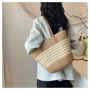 Close-up of woven straw beach tote featuring brown leather straps and striped texture