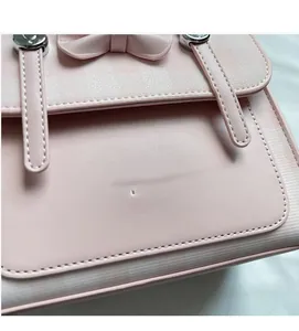 Detail of pink faux leather bag showing bow design, metal accents and fine stitching
