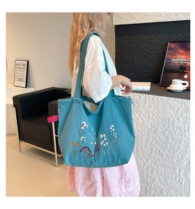Detail of floral embroidery and adjustable drawstring on teal canvas tote bag