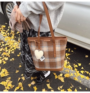 Détail du sac seau à carreaux avec pendentif cœur et bandoulière en décor d'automne