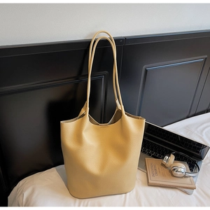 Close-up of a large pale yellow tote bag with litchi grain texture in a lifestyle setting