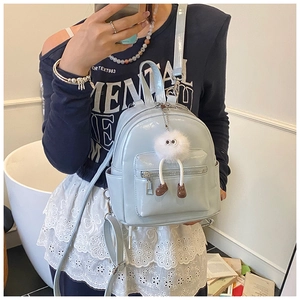 Detail of light blue patent leather mini backpack with cute white plush monster charm
