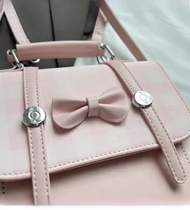 Detailed view of pink plaid backpack featuring a cute bow and metallic hardware