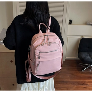 Detailed back view of a pink pebbled faux leather backpack with silver chain zipper pulls