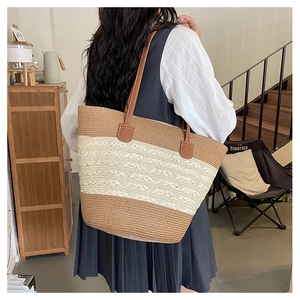 Detail of woven beach tote bag featuring contrasting straw textures and brown leather straps