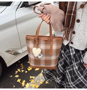 Détail du sac cabas à carreaux avec poignée en cuir marron et breloque en cœur pelucheux