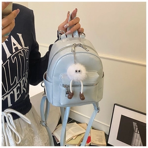 Detailed view of light blue mini patent leather backpack with cute monster plush charm