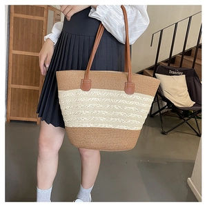 Detail of woven straw beach tote featuring brown and beige stripes and leather handles