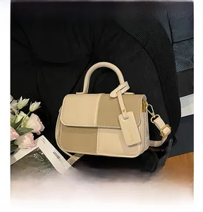 Détail d'un sac bandoulière bicolore avec garniture dorée et étiquette de mode chic