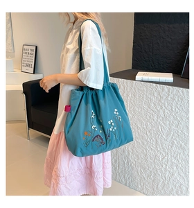 Detail of colorful wildflower embroidery on a dark cyan vintage tote bag with drawstring
