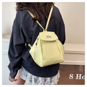 Detail showing the light yellow synthetic leather backpack with metal plate and flap closure