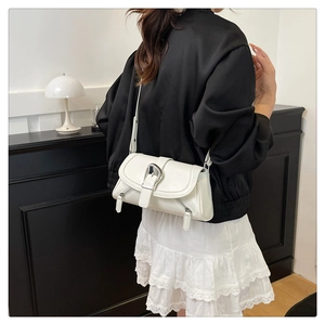 Detail view of white leather shoulder bag with silver buckle and side zipper accents