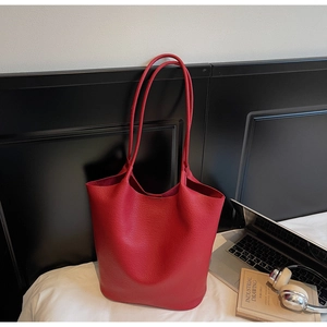 Close-up of red lychee pattern leather bucket bag on a nightstand in a cozy room