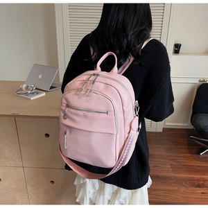 Pink pebbled leather backpack detail with silver zippers and woven patterned strap