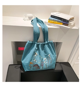 Detail of dark blue drawstring tote bag featuring exquisite floral embroidery and wide strap