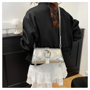 Detail of silver metallic crossbody bag with chrome buckle and decorative side zippers