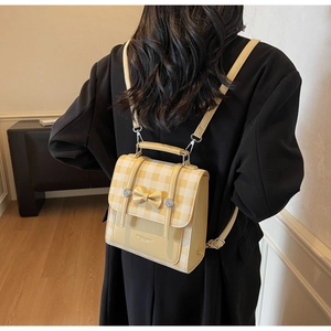 Close-up of yellow and white checkered backpack featuring bow detail and silver hardware