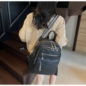 Detail view of black lychee leather backpack featuring multi-layer silver zippers and jacquard strap