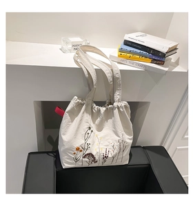 Close-up of colorful floral embroidery and red ribbon detail on canvas tote bag