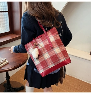 Détail du sac cabas en tweed écossais rouge avec bordure en cuir et cœur pelucheux