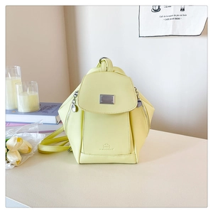 Detail of pale yellow PU leather backpack featuring metal magnetic flap and brand logo