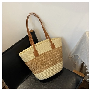 Close-up of woven straw tote bag with brown leather straps and dual-tone texture detail