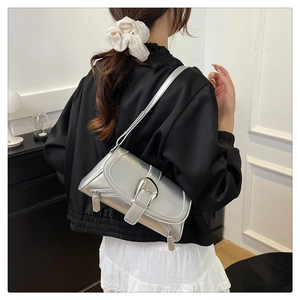 Close-up of silver glossy shoulder bag with metal buckle and decorative side zippers
