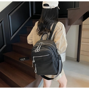 Detail of black pebbled leather backpack with silver zippers and woven geometric strap