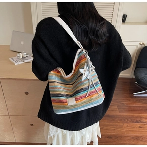 Detalle del bolso de hombro tejido a rayas coloridas con colgante de estrella y correa blanca