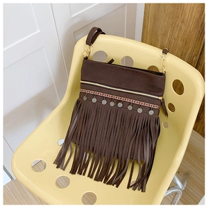 Détail du sac bohème marron foncé avec disques en métal argenté et longues franges en daim