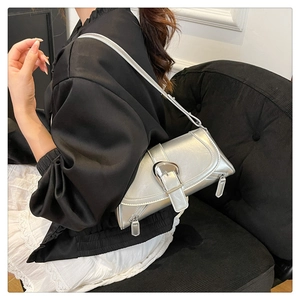 Close-up of metallic silver hobo bag featuring a large metal buckle and zipper detail