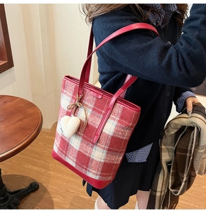 Détail macro du motif écossais rouge et du pendentif cœur doux sur le sac seau