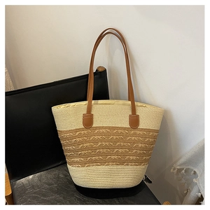 Detail of two-tone woven tote bag with beige raffia texture and brown leather handle