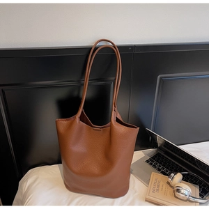 Detailed macro view of caramel brown lychee grain leather tote bag in home office setting