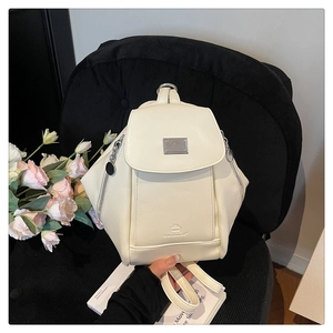Detailed view of the embossed logo and zipper accents on this cream minimalist backpack