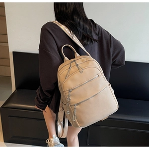 Rear view of model wearing a beige lychee texture leather backpack with woven strap