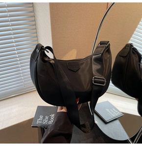 Detail of black nylon crescent bag with adjustable wide strap and logo leather patch