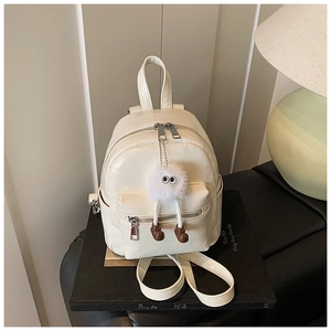 Close-up of beige faux leather mini backpack with silver zipper and plush charm detail