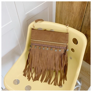 Détail d'un sac bandoulière en daim marron avec broderie ethnique et breloques en métal