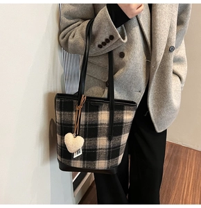 Détail du sac seau en tweed à carreaux avec lanières en cuir noir et breloque cœur