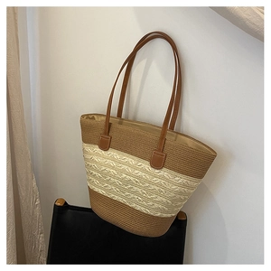 Detail of woven straw tote bag featuring contrast stitching and premium leather handle