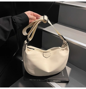 Detail of cream crescent crossbody bag with adjustable wide strap and logo plaque
