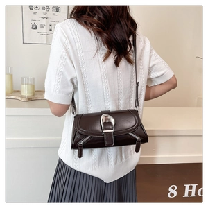 Detail of dark brown leather shoulder bag featuring a large silver metal buckle and side zippers