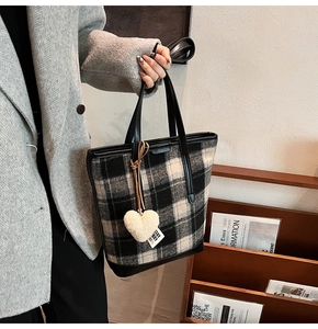 Détail du sac seau en tweed noir et blanc avec breloque cœur et poignée en cuir